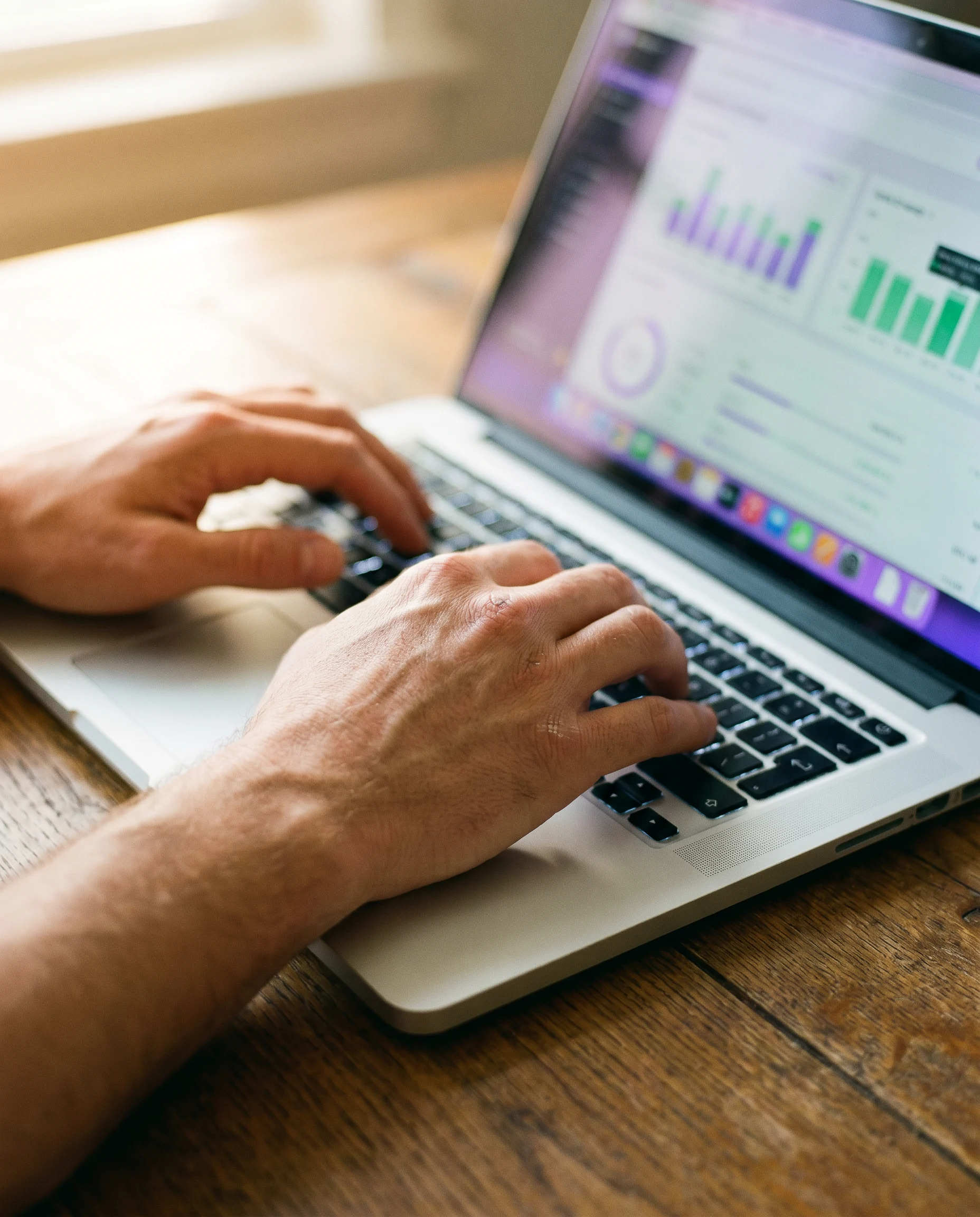 Hände am Laptop mit Analytics-Dashboard, fokussierte Strategie-Arbeit